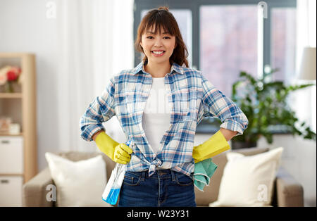 Sorridente donna asiatica la pulizia a casa Foto Stock
