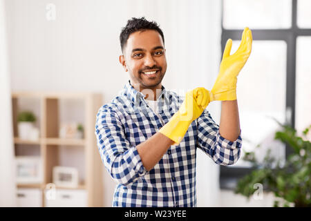 Uomo indiano Mettere guanti protettivi in gomma su Foto Stock