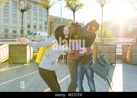 Amici studenti adolescenti con la scuola zaini, divertirsi in modo da scuola. Sullo sfondo della città, ora d'oro Foto Stock