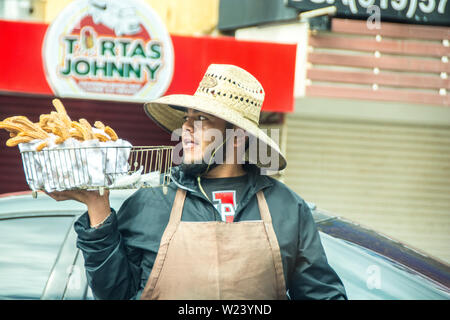 Un uomo messicano vendere churros, al San Ysidro, California e Tijuana, Mexio valico di frontiera; Stati Uniti e Messico. Foto Stock