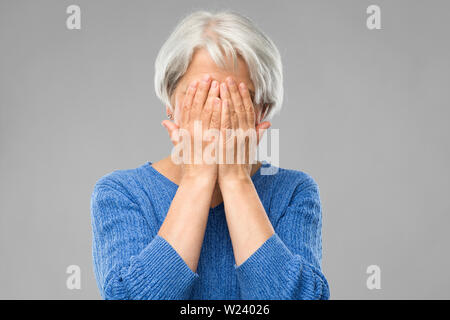 Ha sottolineato il senior donna tenendo alla sua testa Foto Stock