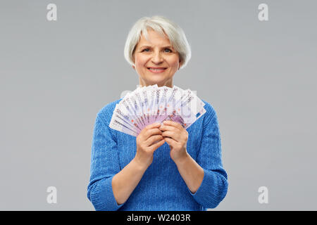 Senior donna con centinaia di euro banconote denaro Foto Stock