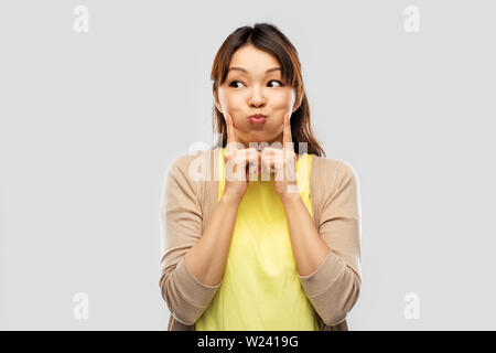 Sorridente donna asiatica rendendo volti e divertirsi Foto Stock