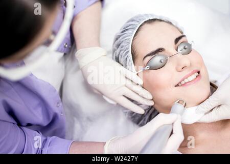 Il dermatologo utilizzando la saldatrice a laser macchina sul volto di donna, close-up. Foto Stock