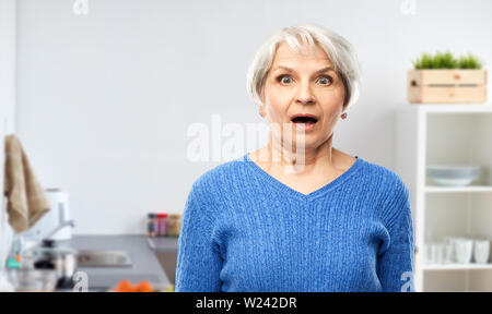 Scioccato senior donna con la bocca aperta in cucina Foto Stock