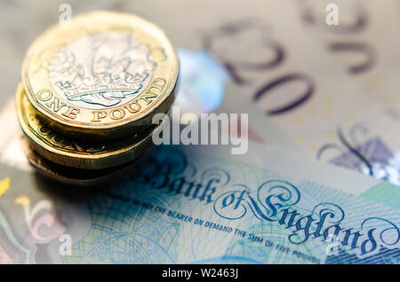 Foto macro di British una libbra di monete sulla parte superiore delle banconote di diverso taglio. Foto Stock