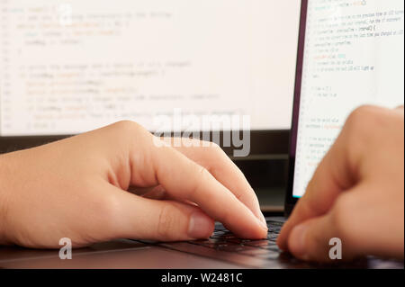 Programmatore rendendo il codice. Mani toccano la tastiera su schermo digitale sullo sfondo dello script Foto Stock