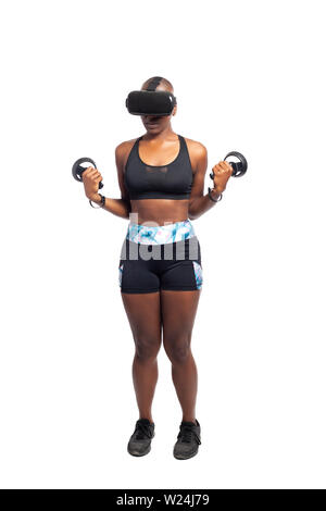 Atletica femmina nero gamer indossare una cuffia vr e di esercitare in una realtà virtuale palestra per la perdita di peso. L'immagine illustra la tecnologia utilizzata nello sport Foto Stock
