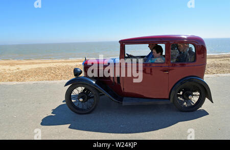 Rosso classico Austin auto sette essendo condotta lungo la passeggiata sul lungomare. Foto Stock