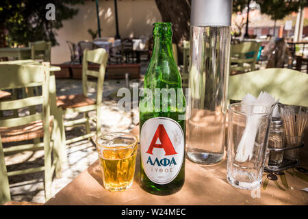 Andritsaina, Grecia. Una bottiglia e bicchiere di birra alfa su un tavolo in un ristorante Foto Stock