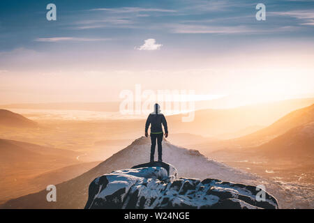 Gli uomini di ammirare il tramonto dalla cima di Slieve Bearnagh nella Mourne Mountains Irlanda del Nord Foto Stock