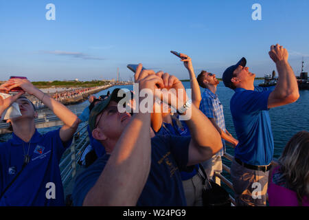 La folla di spettatori prendere le foto della fotocamera in corrispondenza di Jetty Park come la NASA Orion il lancio del sistema di interruzione di blasti off sulla cima di un Northrop Grumman rocket booster Luglio 2, 2019 in Cape Canaveral, in Florida. Il volo di prova hanno dimostrato che il sistema di interruzione può tirare l'equipaggio per la sicurezza nel caso improbabile di un'emergenza durante la salita aprendo la strada a un lancio del nuovo Orion sistema di lancio. Foto Stock