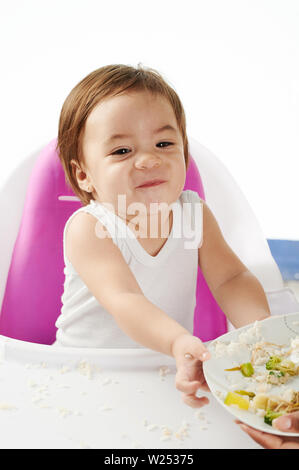 Baby rifiutano di mangiare il cibo sulla piastra seduta alta sedia isolato Foto Stock