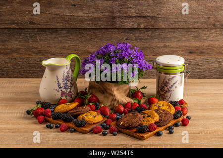 Frutti di bosco, cioccolato i biscotti con la campanula e Caraffa in ceramica Foto Stock