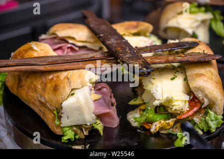 Calorie deliziosi panini da materia organica baguette francesi che sono farciti con prosciutto, pomodori, formaggi, insalate e spezie cotta su una piastra in modo che fa Foto Stock