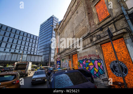 Bucarest, Romania - Luglio 07, 2019: un alto e moderno edificio, chiamato il marchio Tower, in contrasto con alcuni vecchi edifici situati in una strada a Bucha Foto Stock
