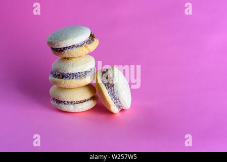 Deliziosi biscotti argentino alfajores con crema dulce de leche vicino sul tavolo. Bianco amaretti di vaniglia su sfondo rosa. Il francese Delicato dessert per la prima colazione nella luce del mattino. Foto Stock