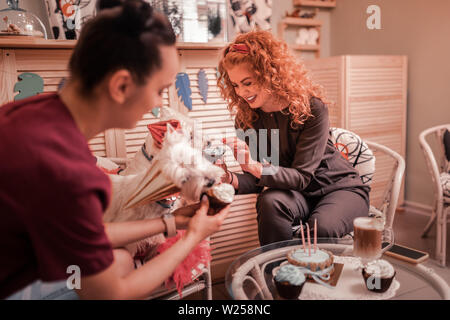 Festeggia il compleanno. Due donne festeggia il compleanno dei loro cani con tortine e cappuccino Foto Stock