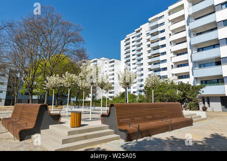 Case residenziali e piccole accogliente giardino con alberi in fiore e panchine di legno a Berlino, Germania. Foto Stock