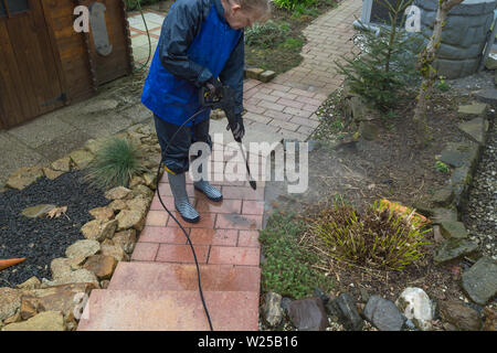 La donna pulisce in lastre di pietra con un lavaggio a pressione Foto Stock