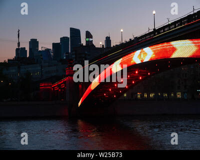 Mosca, Russia - aprile 2019. Illuminazione su Smolenskiy Metropolitan Ponte e sagome di grattacieli di notte Foto Stock