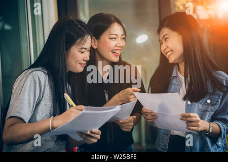 Asian più giovane donna freelance parlando con toothy volto sorridente in ufficio in casa Foto Stock