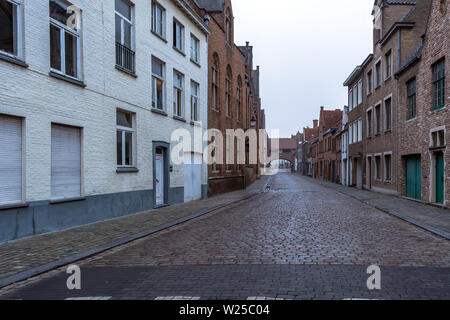 Pittoresca strada vecchia di Bruges con tradizionali case medievali e la strada di ciottoli in una leggera nebbia mattutina. La città di Bruges strade. Foto Stock