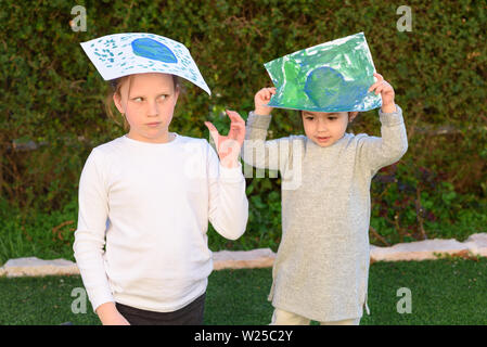 Ritratto di due simpatici bambine tenendo il disegno globo terrestre. I bambini dipingere un quadro di terra. Plastica mondo libero concetto. Foto Stock