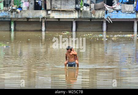 Dimapur, India. 06 Luglio 2019: un uomo porta altri sulla sua schiena wade acqua di inondazione area a Naga Shopping Arcade in Dimapur, India nord orientale di stato del Nagaland. Il Monsone di pioggia che ha colpito il Sud Est Asiatico regione da giugno a settembre provoca enorme disastro ogni anno. Credito: Caisii Mao/Alamy Live News Foto Stock