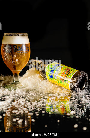 Peniscola, Castellon, Spagna, Maggio 08, 2019: Freddo gustoso e schiuma di birra in un bicchiere di birra e una bottiglia di Badum su sfondo scuro. E una riflessione Foto Stock