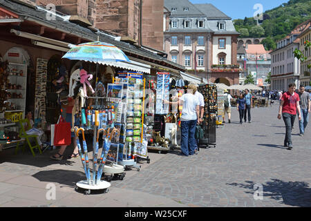 I turisti alla ricerca di negozi di souvenir che offre vari locali ninnoli al marketplace in una giornata di sole in Heidelberg, Germania Foto Stock