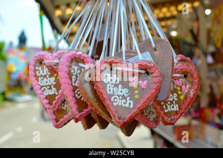 A forma di cuore caramella di panpepato decorate con colorati glassa di zucchero e "ti amo", scritto in tedesco su di essi appeso dal cibo stand al luna park Foto Stock