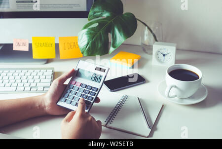 Le persone che lavorano con la calcolatrice sul piano di lavoro in ufficio. business plan, concetti finanziari Foto Stock