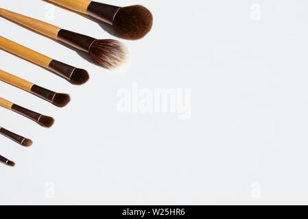 Make up set di spazzole disposte in una linea. Naturale con legno di bambù maniglie. Copia spazio su uno sfondo bianco. Foto Stock