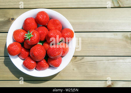 Le fragole su un di legno tavolo da picnic - giardino estivo mangiare concetto. Foto Stock