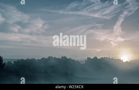 Tramonto su un piccolo lago con la nebbia sopra l'acqua. Foto Stock