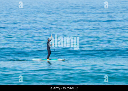 Stand Up Paddle boarder muta in kayak sul mare. Immagine minimalista. Foto Stock