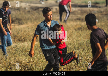 5 luglio 2019 - Gaza, Palestina. 05 luglio 2019. Dimostranti palestinesi scontro con le forze israeliane durante questo Venerdì di grande marzo di tornare nel rally di Malika area a est della città di Gaza. Migliaia di palestinesi aveva fatta convergere in differenti siti vicino alla frontiere Gaza-Israel per unirsi alla protesta. Alcuni dei manifestanti hanno lanciato sassi verso i soldati israeliani di stanza sull'altro lato della recinzione che hanno risposto con gas lacrimogeni e proiettili di ferire decine di dimostranti palestinesi. Dimostranti palestinesi hanno organizzato una grande Marcia di protesta di ritorno dal 30 marzo scorso anno Foto Stock