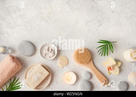 Spa concept, piatto adagiare sulla pietra bianca di sfondo, foglie di palmo, fiore, candela e zen come pietre grigie, vista dall'alto. Foto Stock