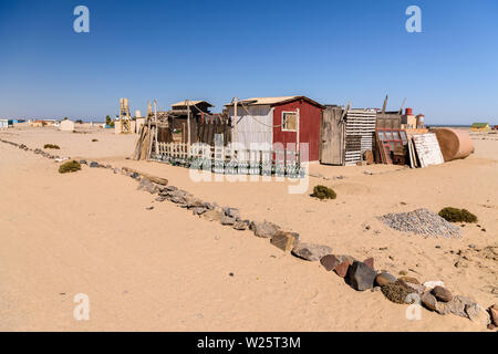 Numero elevato di vino vuote e bottiglie di birra al di fuori di una casa ramshackled sparso sul mare del villaggio vacanze di Wlotzkasbake, Skeleton Coast, Namibia Foto Stock