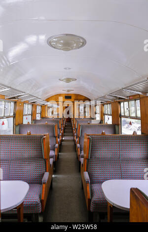 All'interno di un'annata carrozza ferroviaria con un sacco di legno, rivestita posti a sedere e tavoli. Foto Stock