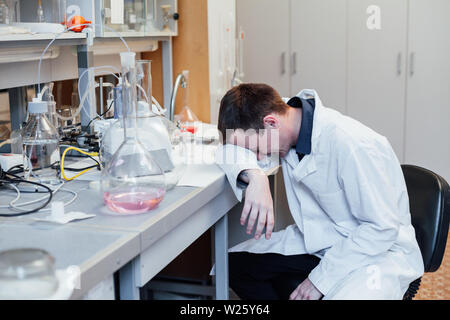 Scienziato dorme durante il lavoro in laboratorio Foto Stock