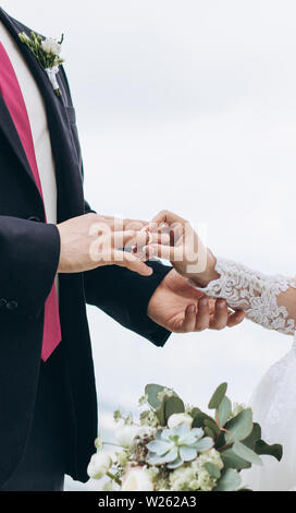 La sposa mette l'anello al dito lo sposo. Evento di nozze. Foto Stock