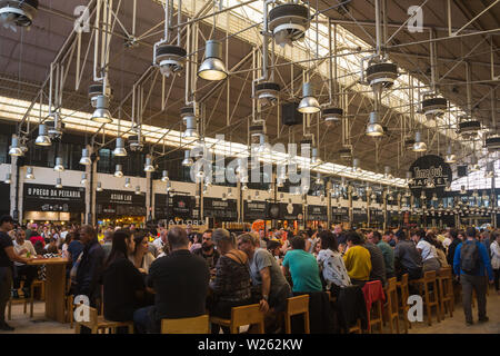 Interior food court del tempo fuori mercato nel vecchio Mercardo da Ribeira, Lisbona, Portogallo occupato con le persone che si godono la vasta gamma di prodotti alimentari offerti Foto Stock