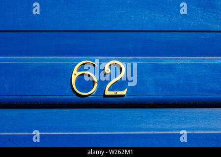Casa numero 62 con il sessantadue in cifre di metallo su un luminoso in legno di colore blu della porta anteriore Foto Stock