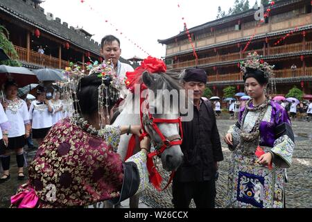 (190706) -- QIANDONGNAN, Luglio 6, 2019 (Xinhua) -- una donna di Dong gruppo etnico cravatte di seta di una sfera di un cavallo durante un raduno in Leli township di Rongjiang County, a sud-ovest della Cina di Guizhou, Luglio 6, 2019. La popolazione locale di Dong gruppo etnico frequentare la raccolta per contrassegnare il Festival Xiangsi. (Foto di Yang Chengli/Xinhua) Foto Stock