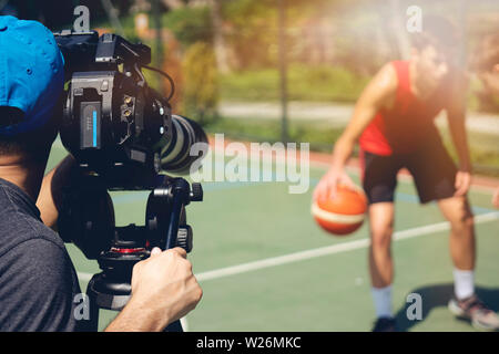 Immagini sfocate di le riprese video o la produzione video e film equipaggio del team con attrezzatura telecamera in posizione esterna e leggero effetto flare. Foto Stock