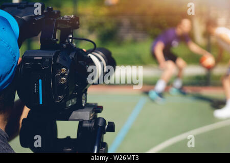 Immagini sfocate di le riprese video o la produzione video e film equipaggio del team con attrezzatura telecamera in posizione esterna e leggero effetto flare. Foto Stock