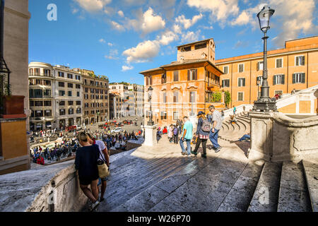 Un giovane si sofferma sulla Scalinata di piazza di Spagna a Roma, Italia, come turisti passano da, con la Piazza di Spagna riempito con i turisti in vista di seguito. Foto Stock