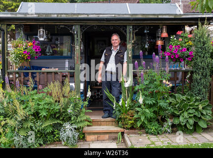 Ritratto di Jim e la sua casa fatta bothy nel giardino della sua casa. Foto Stock